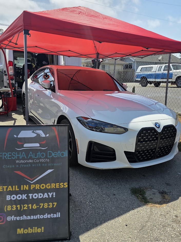 White BMW at a FRESHA mobile detailing setup under a red canopy